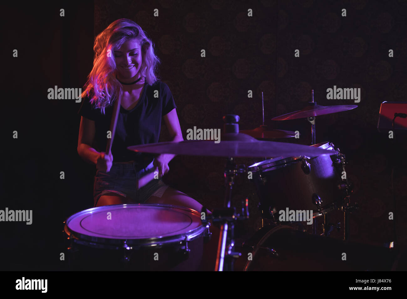 Beautiful female drummer performing on stage in Stock Photo