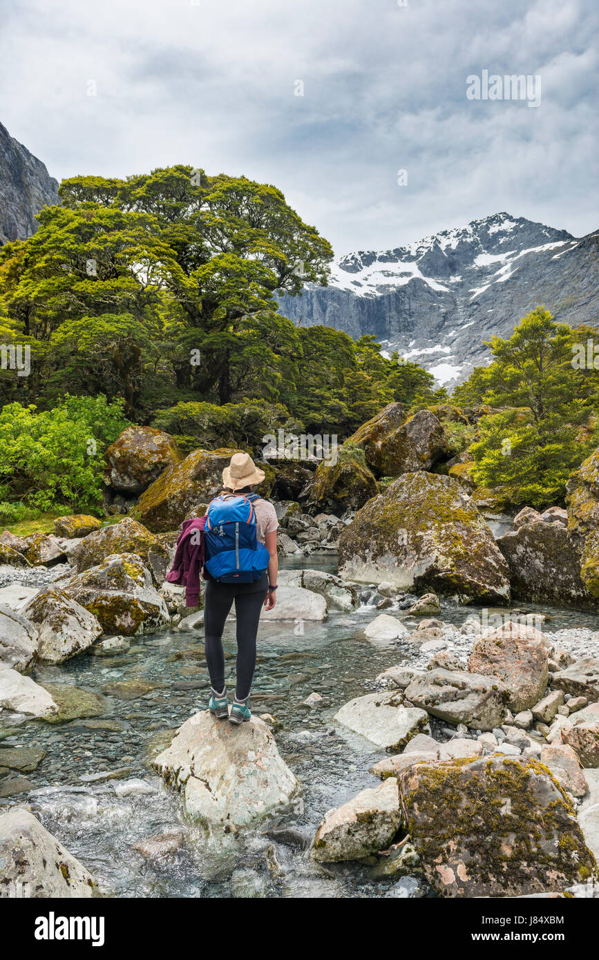 Female hiker on a rock in the river, Fiordland National Park, Southland, New Zealand Stock Photo