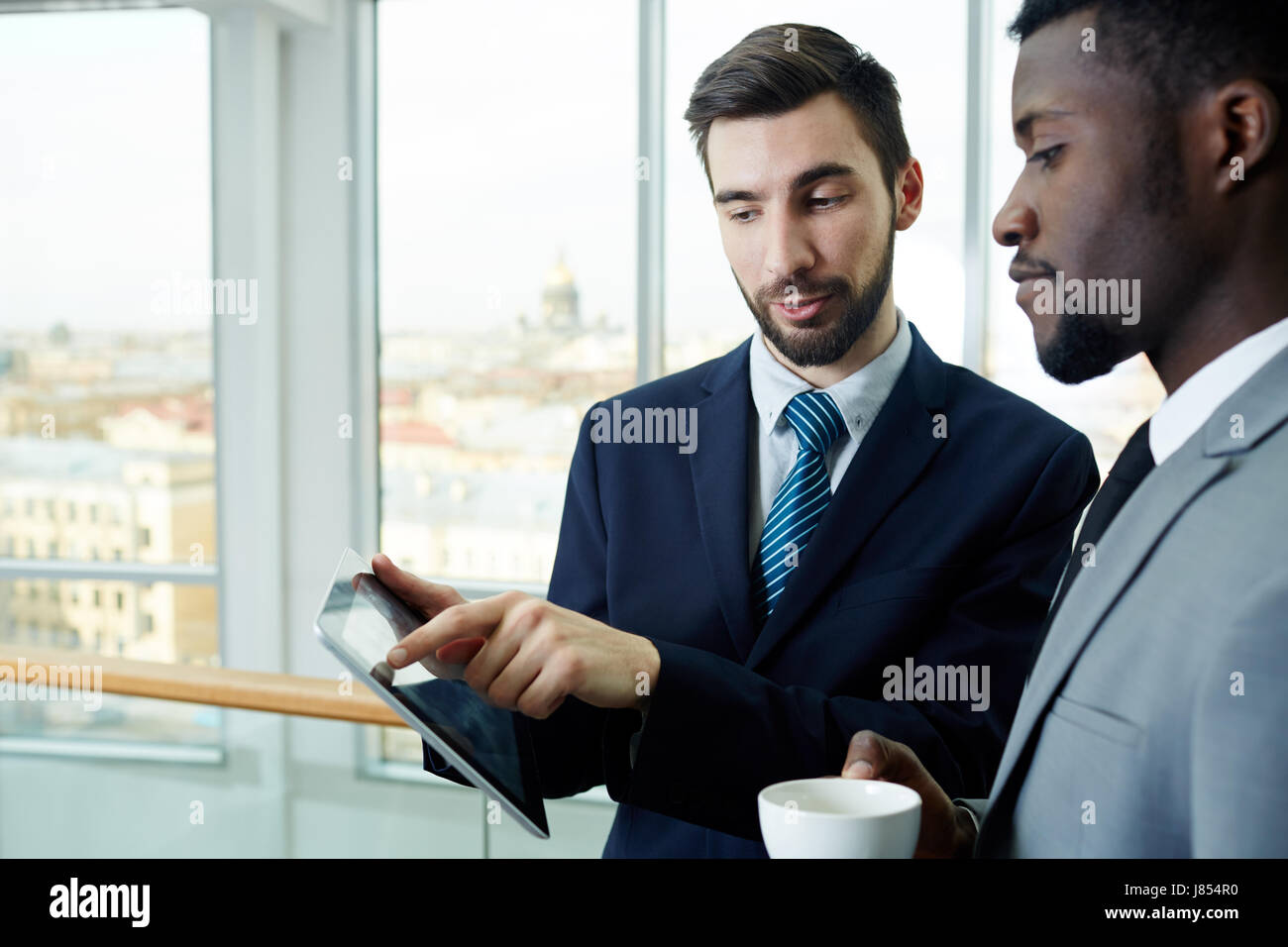 Portrait of handsome bearded businessman pointing to digital tablet ...
