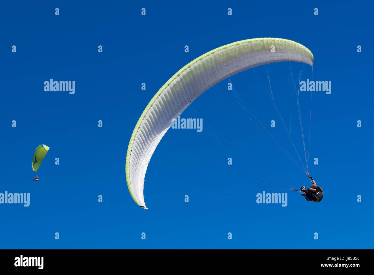 Couple of two paragliding athletes in the blue sky. Stock Photo