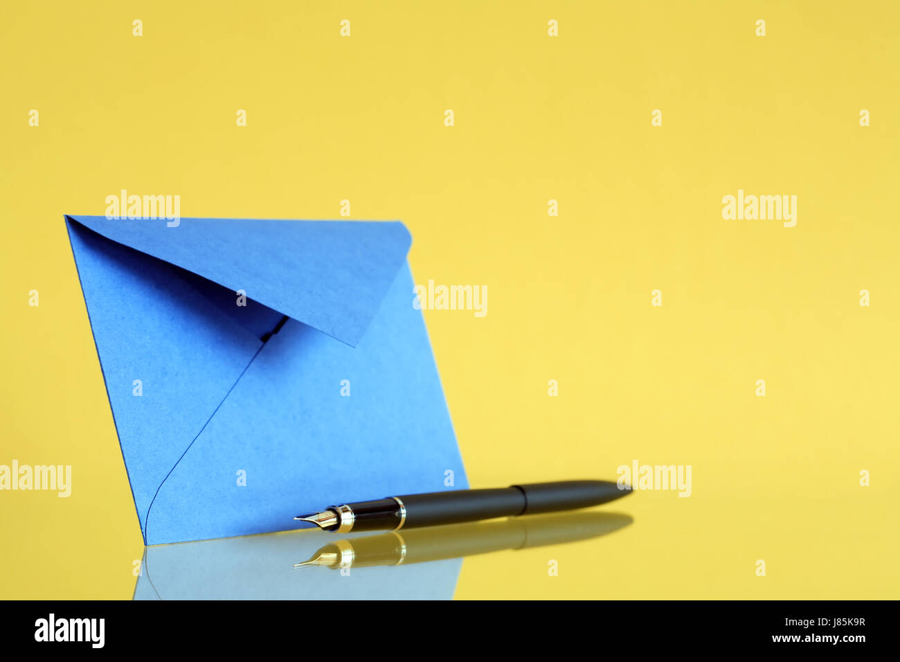 Blue envelope near fountain pen on yellow background Stock Photo