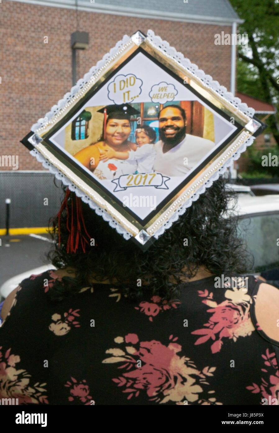 A young woman on the way to her college graduation wearing a cap acknowledging the help of her significant other and child. In Bayside, Queens, NYC Stock Photo