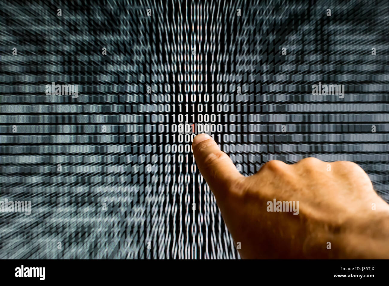 Finger pointing at a red bit figuring a bug a binary code on a screen Stock Photo