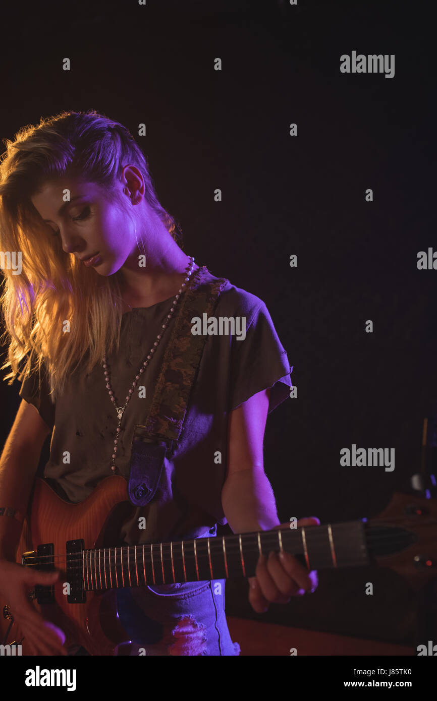 Beautiful female musician playing guitar at music concert Stock Photo