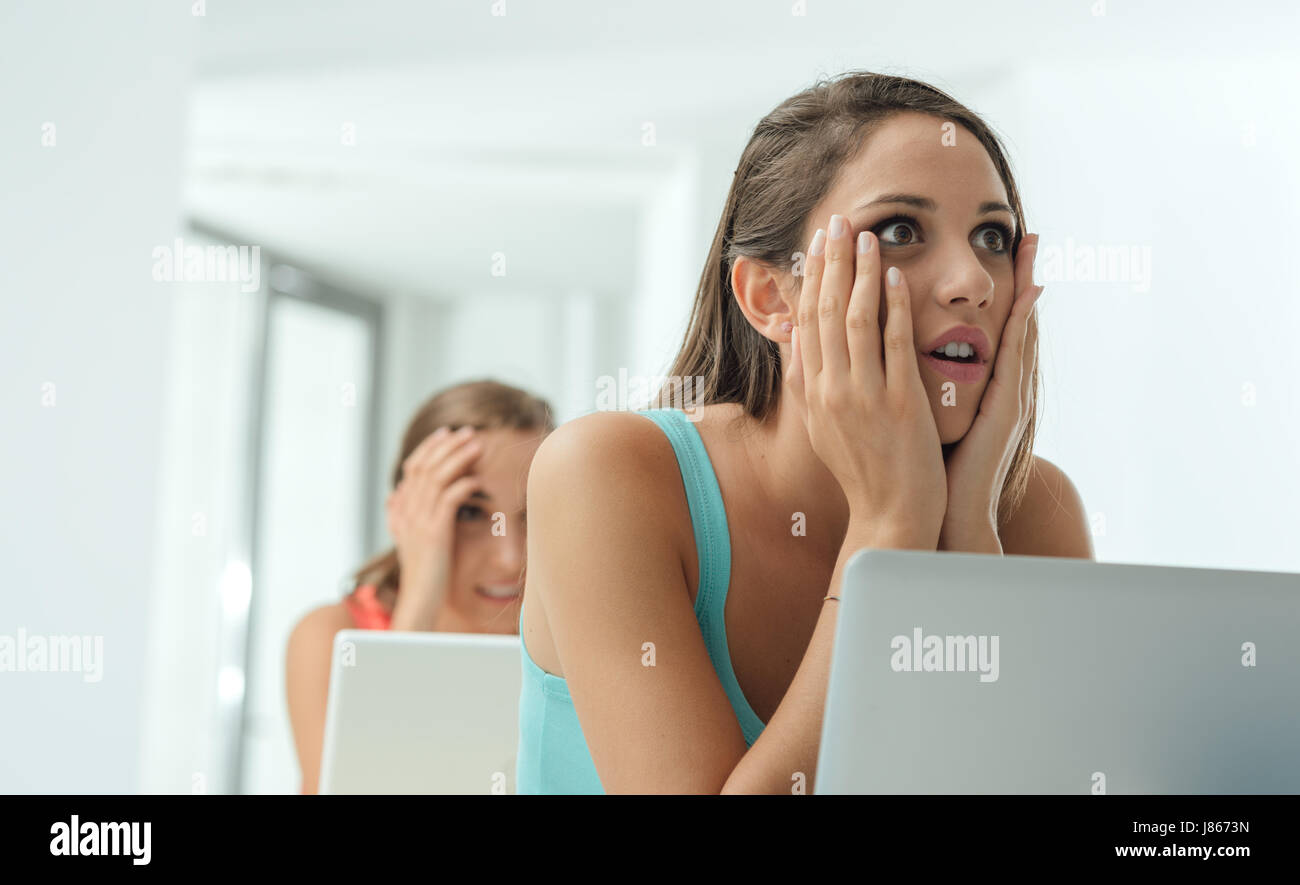 Shocked unhappy girls at school sitting at desk receiving bad news from their professor Stock