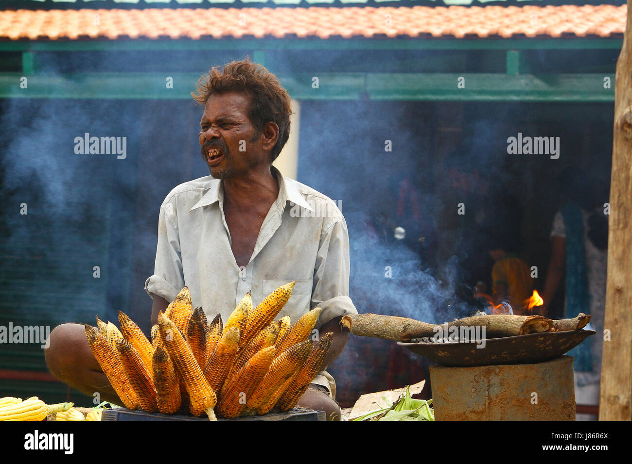 A street vendor selling roasted corn on a hot sunny day in the streets of India to earn his livelihood Stock Photo