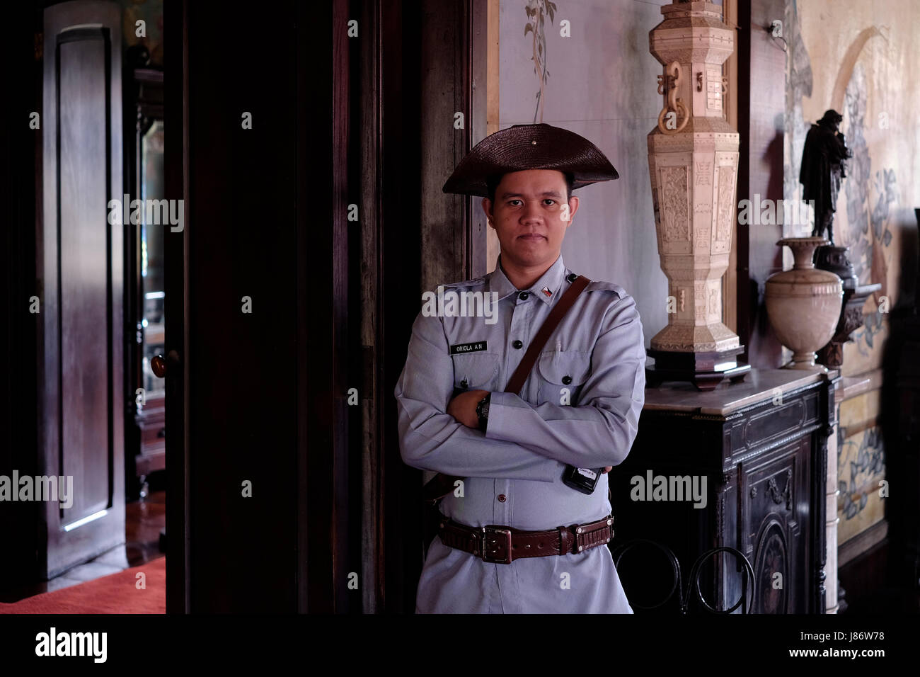 A uniformed Filipino guard dressed as a soldier of the Spanish colonial period stands inside Casa Manila, containing late 19th century and early 20th century furniture found in a typical  Filipino-Hispanic class home located at Plaza San Luis complex representing different eras in Filipino-Hispanic architecture located inside the walled city of Manila referred to as Intramuros in the city of Manila capital of the Philippines Stock Photo