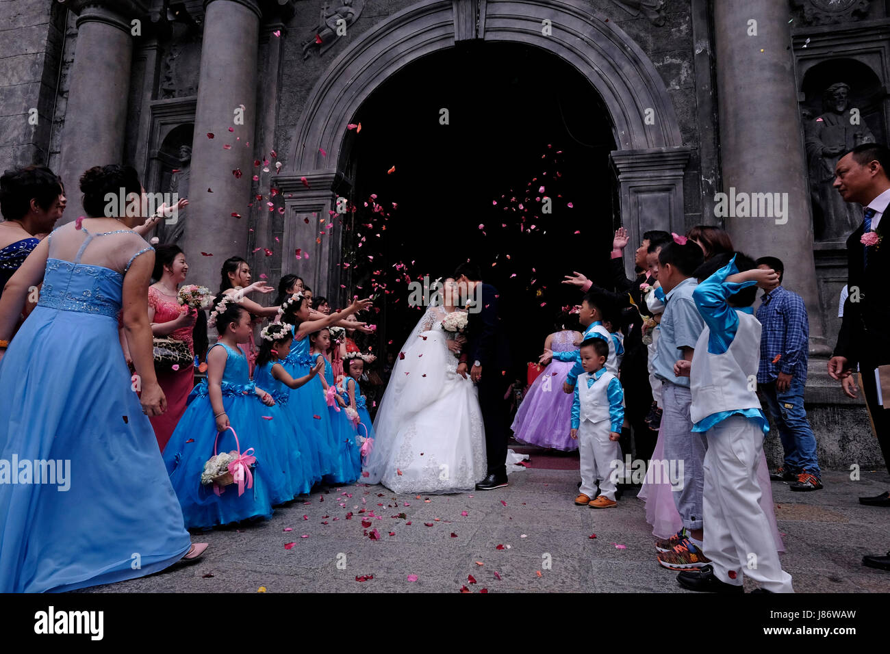 Guests throwing confetti over bride and groom during a Chinese wedding at the Roman Catholic San