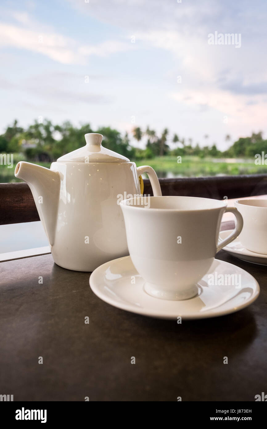White ceramic tea pot ,cups and saucers placed on dark brown color