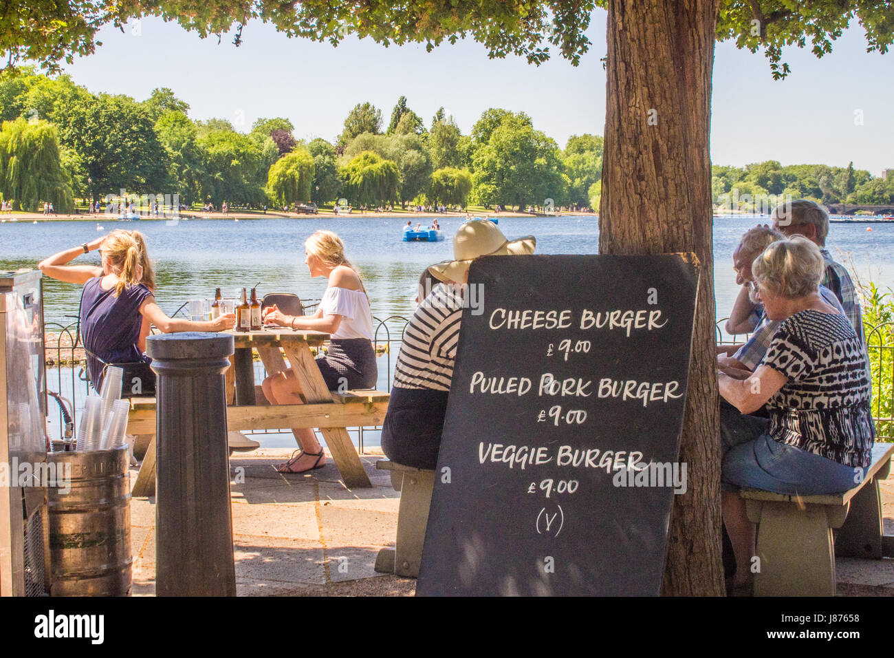 People sitting at an outdoor restaurant by the Serpentine Lake in Hyde Park, London Stock Photo
