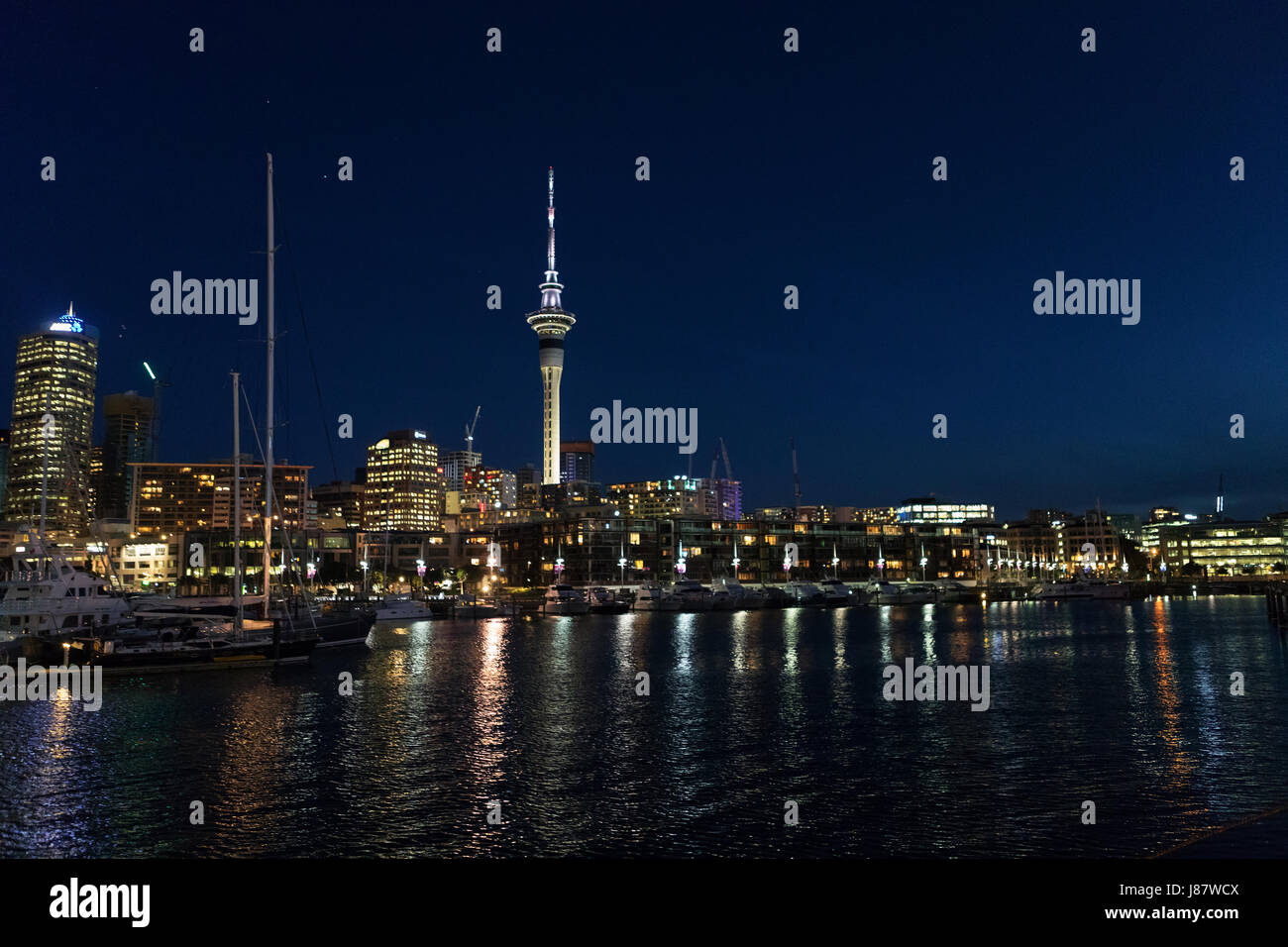 view of Auckland New Zealand city and sky tower at night with lights reflecting in the harbor Stock Photo