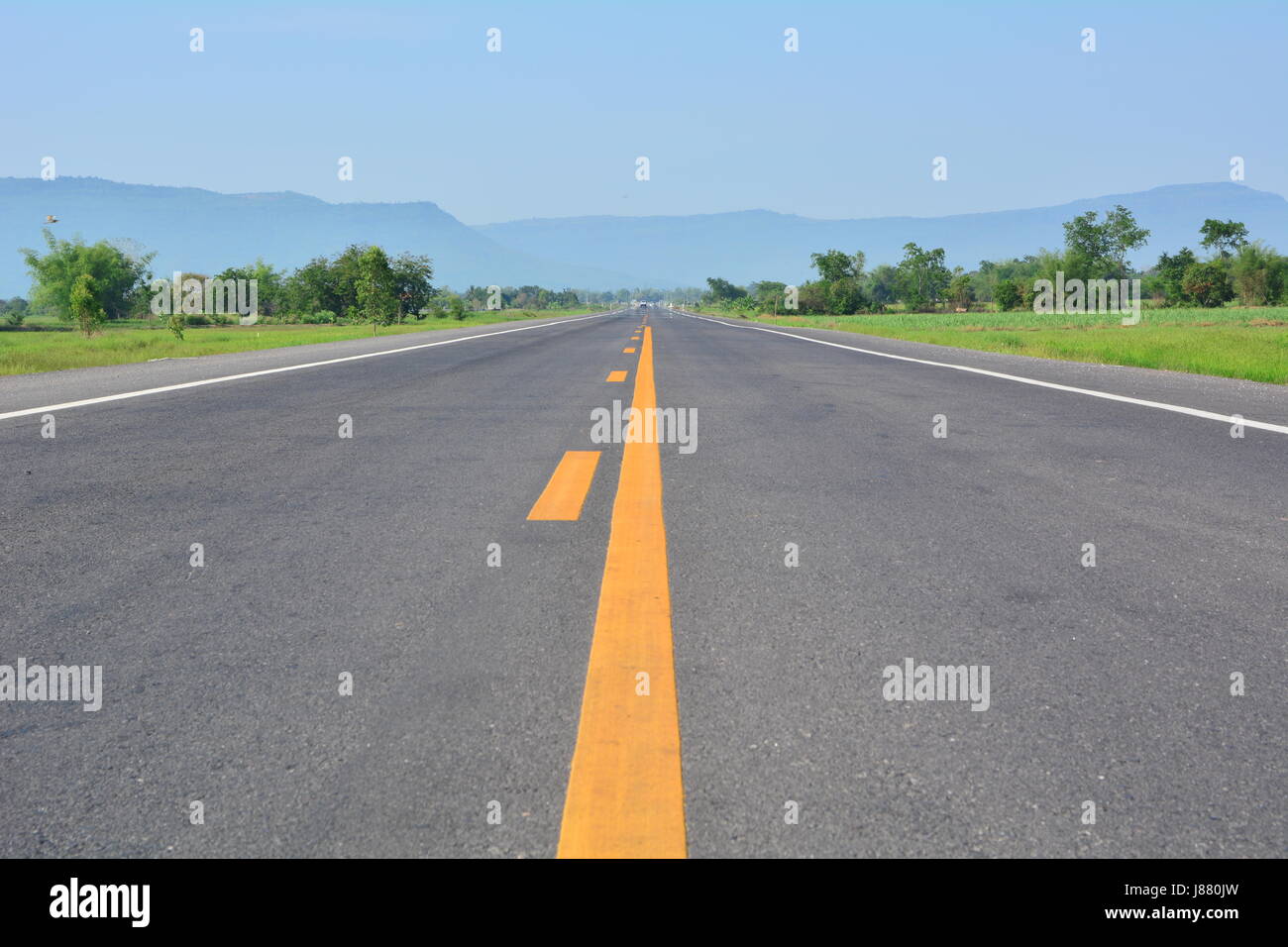 asphalt road through the green field and clouds on blue sky in summer ...