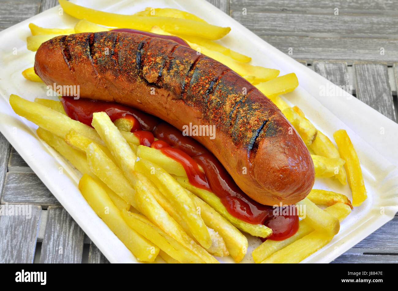 fried sausage with french fried potatoes and ketchup on paper plate, close up, macro, full frame Stock Photo