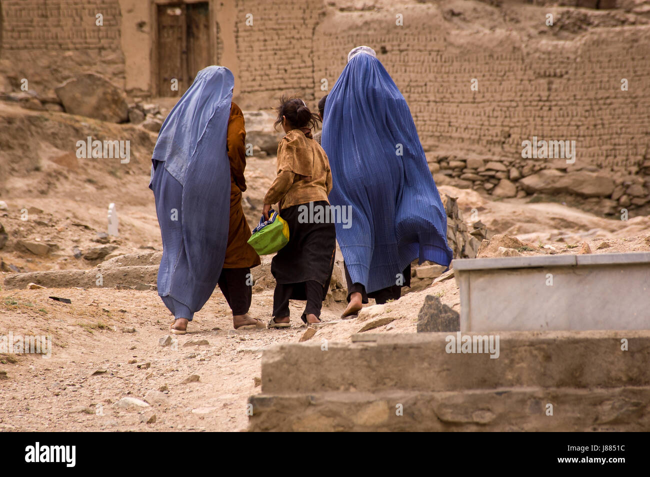 Girls and women in burqas walk through a graveyard near Kabul, Afghanistan Stock Photo
