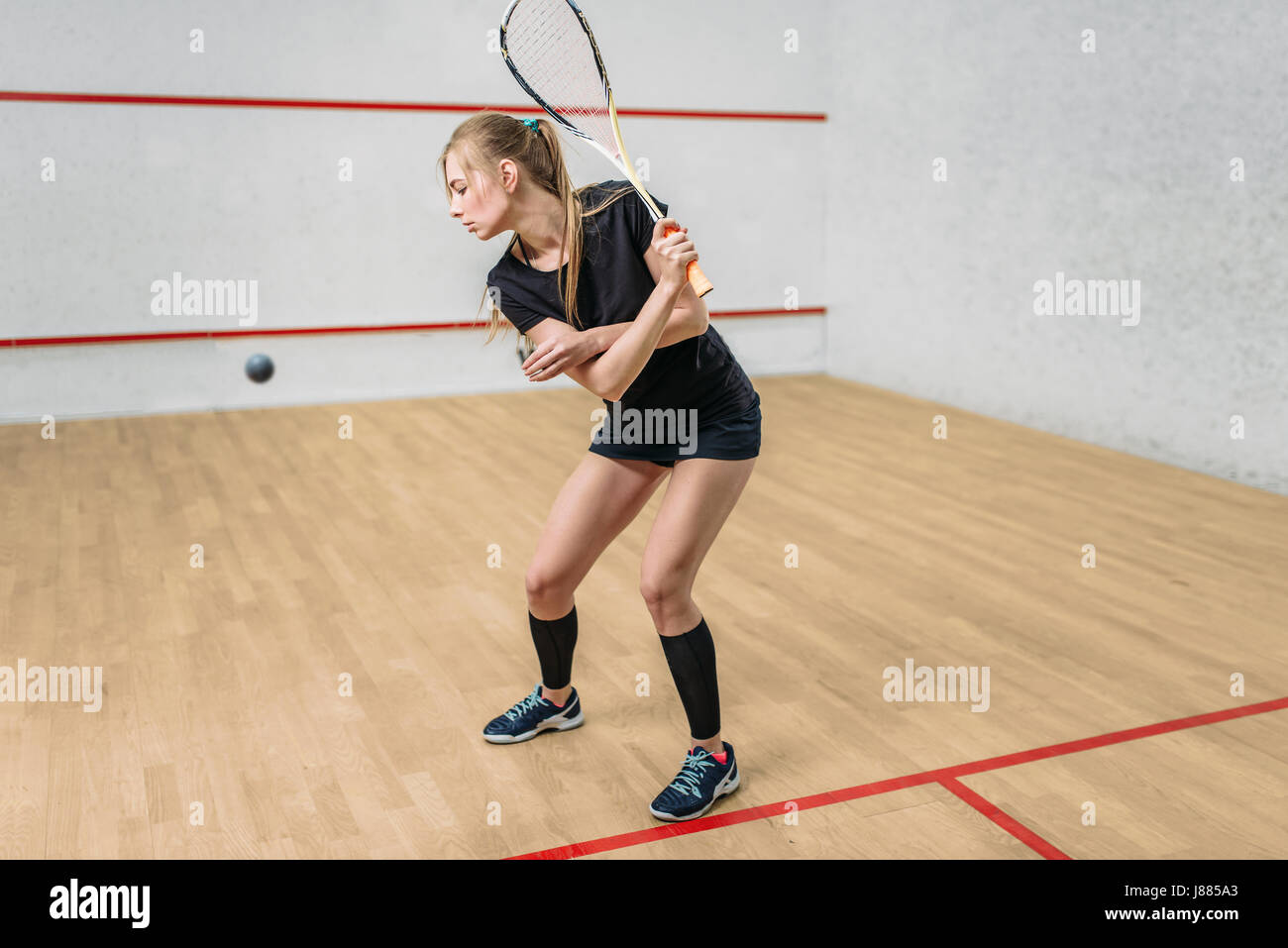 Squash game training, female player with racket in hands, indoor sport