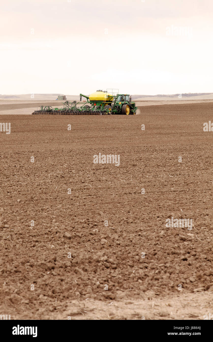 A tractor pulling farm machinery, planting wheat in the fertile farm fields of Idaho. Stock Photo