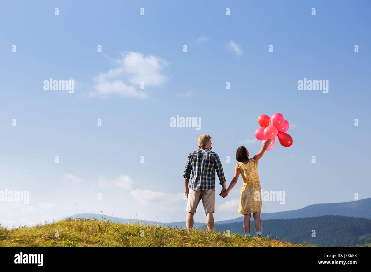 Young loving couple with balloons on sky background Stock Photo - Alamy