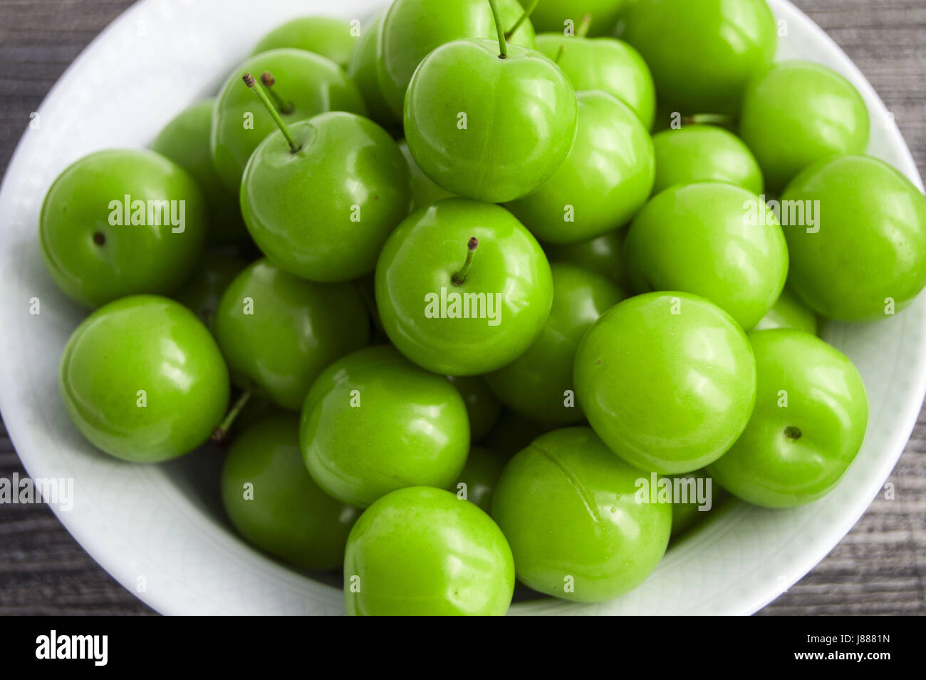 Green sour plums in the plate, plum pictures on the white ground Stock