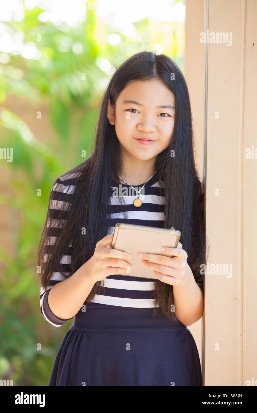 twelve years old asian kid standing with happiness smiling face and tablet computer in hand use for modern life of education and livestyle Stock Photo