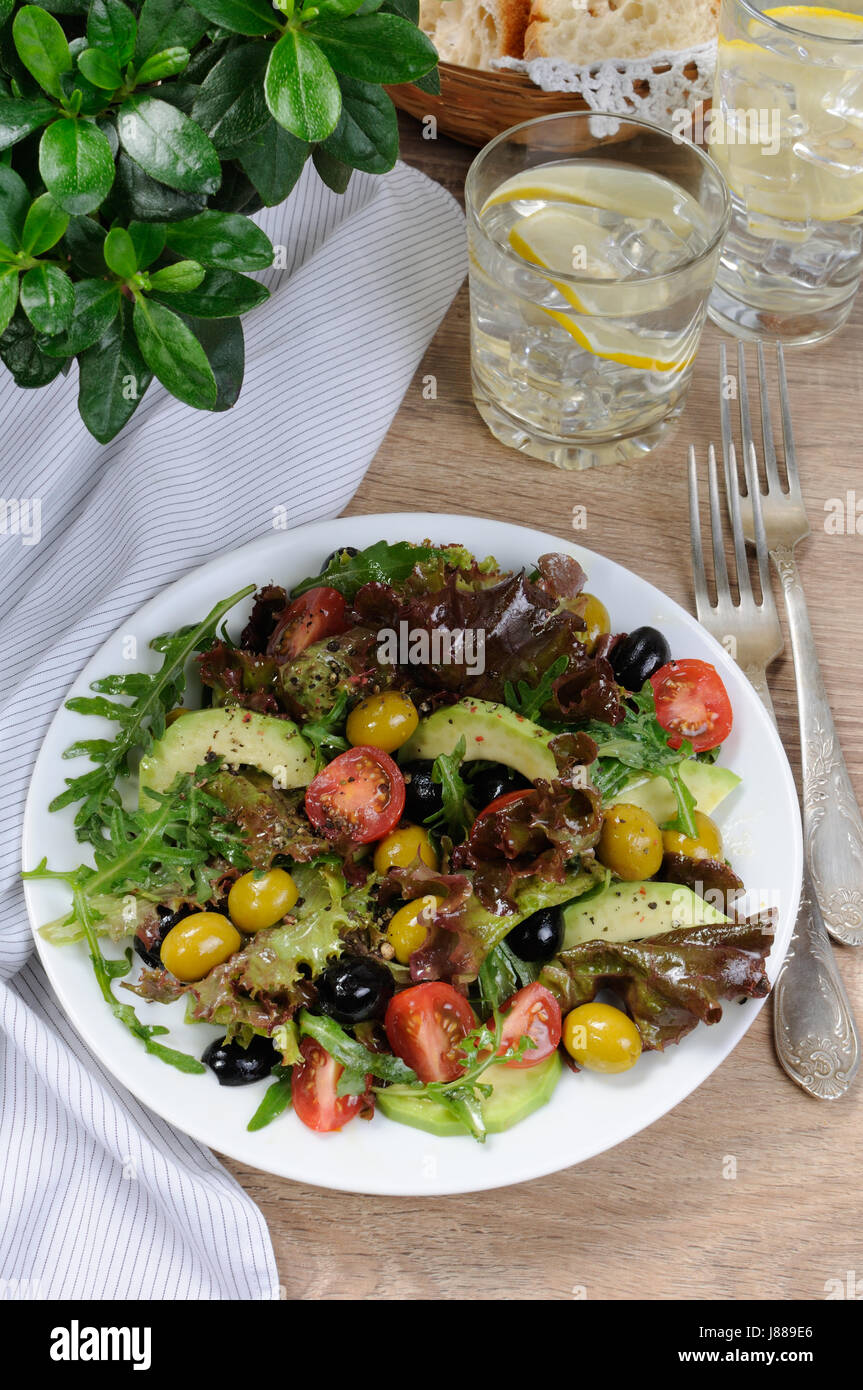 Summer salad - with avocado, olives, tomatoes in lettuce dressed, mustard-garlic sauce Stock Photo