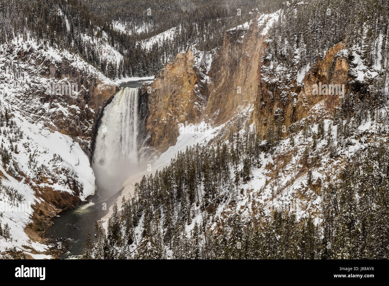 A late spring snow dusts the hills around the Lower Falls of the Yellowstone River as it crashes into the canyon below at Yellowstone National Park April 28, 2017 in Yellowstone, Wyoming. The Lower Yellowstone Falls is the largest volume waterfall in the Rocky Mountains of the United States. Stock Photo
