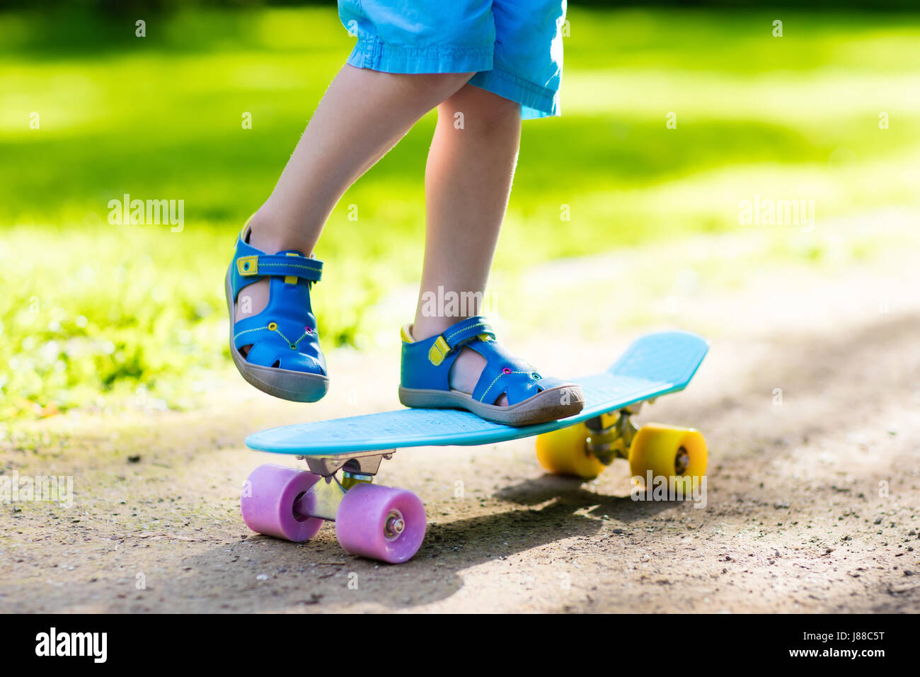Child riding skateboard in summer park. Little boy learning to ride ...