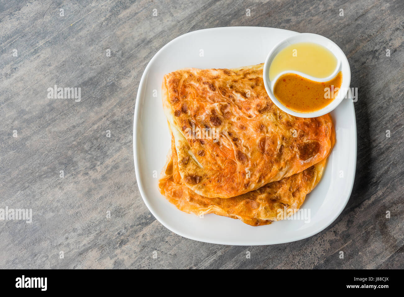 Indian Roti Prata with Condensed milk and Curry Sauce, close up of rustic Indian Roti fried pancake Stock Photo