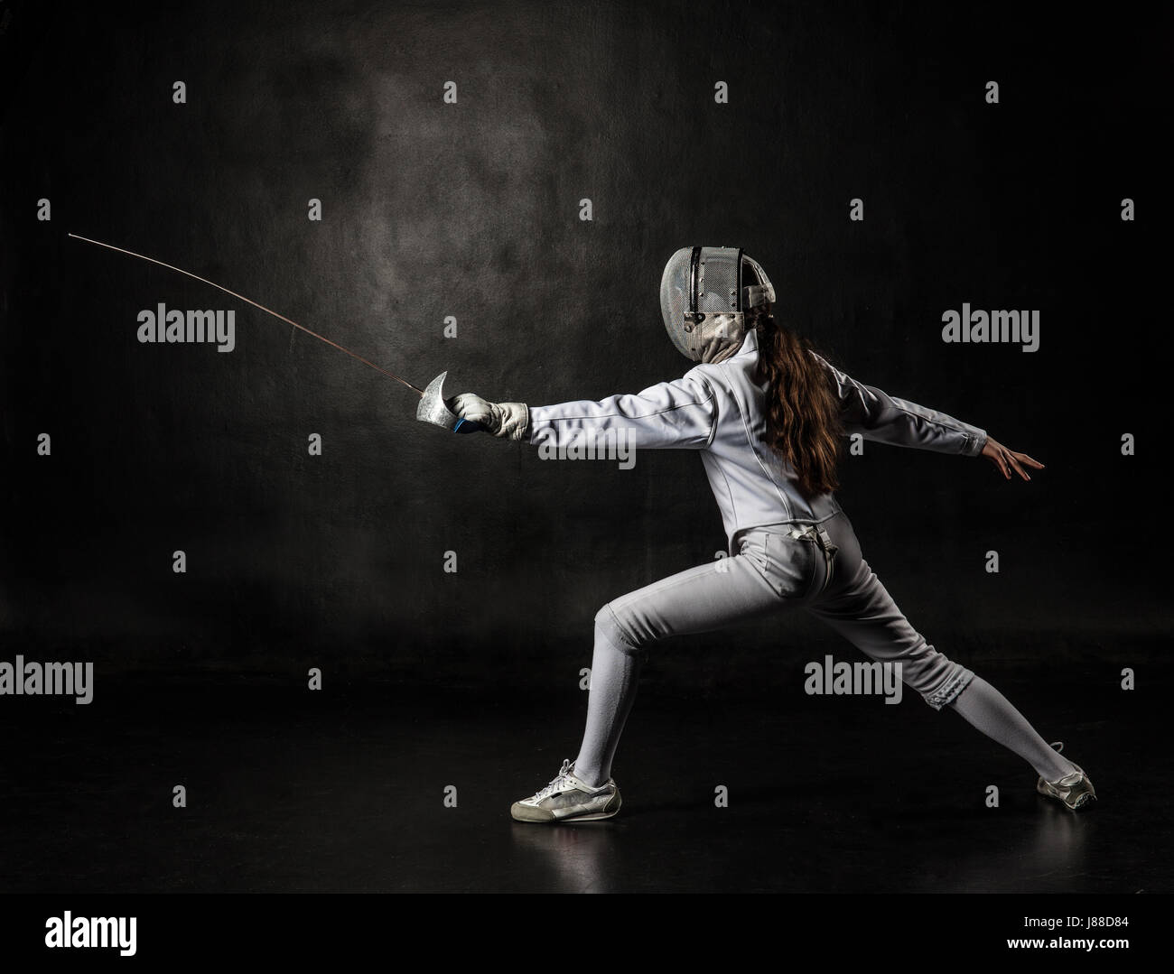 Female fencer wearing white fencing costume isolated on black