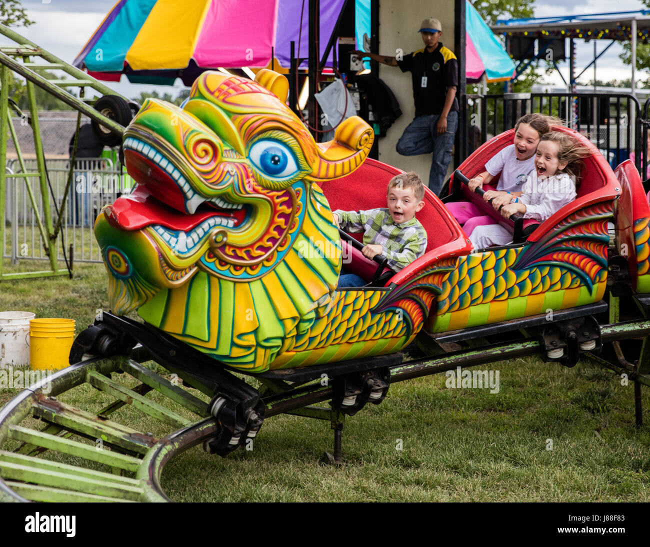 Children and adults enjoying a ride on the midway at the county fair ...