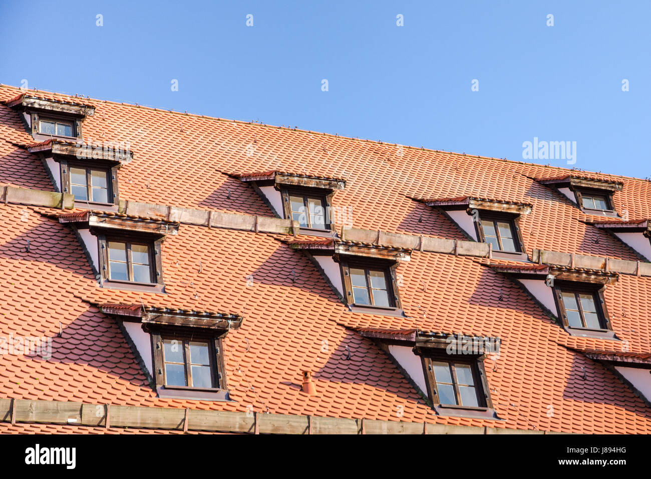 Tiled roof with mansard windows of attic rooms in antique European house Stock Photo