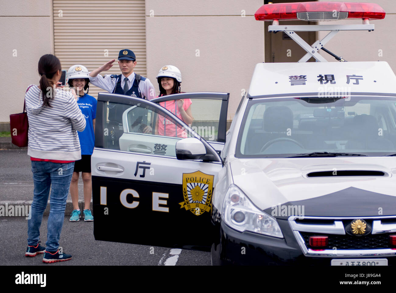 A family poses for photo with a Japanese police officer during a Police Week event, May 17, 2017, at Yokota Air Base, Japan. The event included various static displays from the Tokyo Police Department, Japan Air Self Defense Force, 374th Security Forces Squadron and U.S. Office of Special Investigations. (U.S. Air Force photo by Airman 1st Class Donald Hudson) Stock Photo