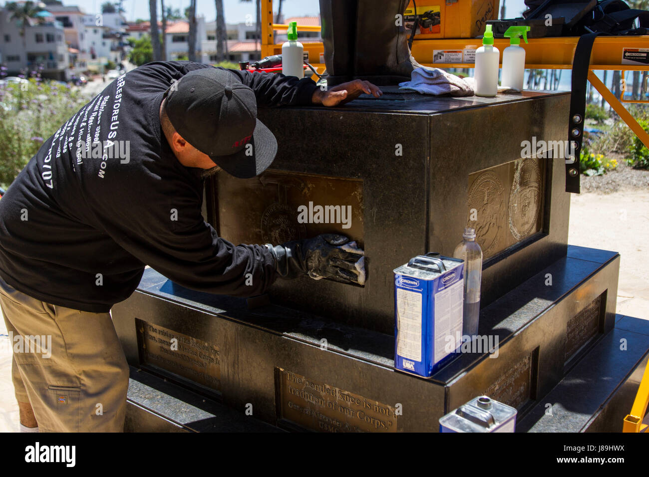 Mr. Jay Solis cleaning the bronze plaques on a memorial during a