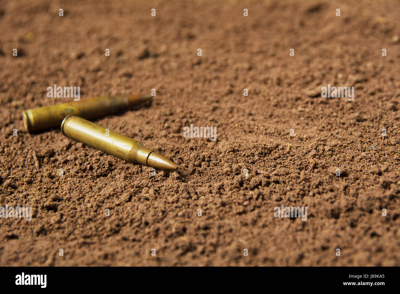 Two bullets, machine gun bullets on soil background Stock Photo