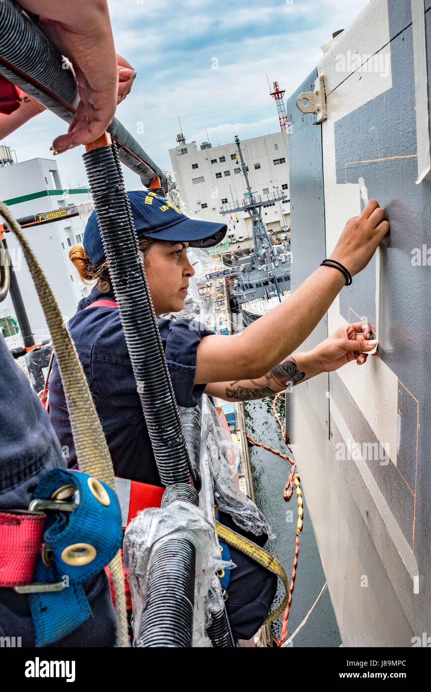 170523-N-JH293-006 SASEBO, Japan (May 23, 2017) Operations Specialist 2nd Class Danielle Hall tapes the outline of the Battle Effectiveness 'E' Award on the port bridgewing of the amphibious transport dock USS Green Bay (LPD 20). Green Bay is forward-deployed to Sasebo, Japan, serving forward to provide a rapid-response capability in the event of a regional contingency or natural disaster. (U.S. Navy photo by Mass Communication Specialist 1st Class Chris Williamson/Released) Stock Photo