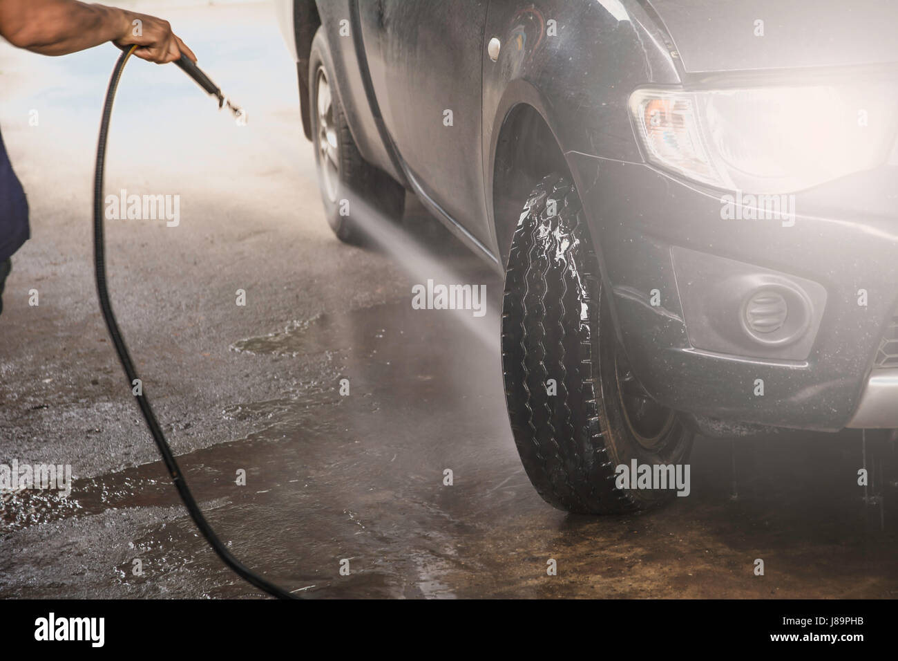 Washing black car by high pressure water. Car wash closeup Stock Photo