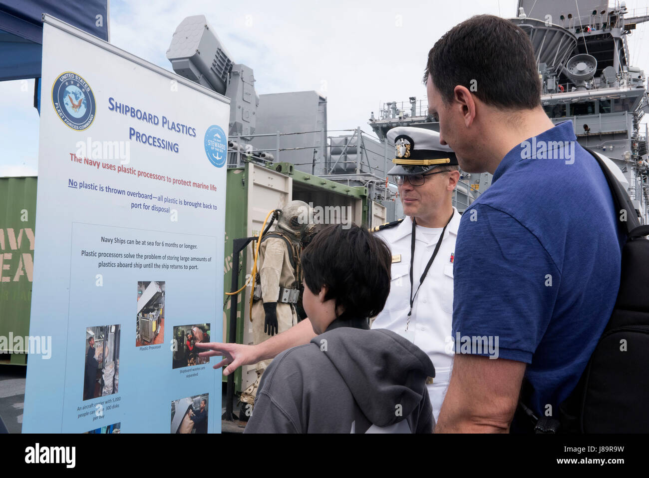 170526-N-MS174-001 NEW YORK (May 26, 2017) Lt. Cmdr. James McLeod, a public affairs officer assigned to U.S. Fleet Forces Command, discusses shipboard plastic processing with visitors at the U.S. Navy’s “Stewards of the Sea: Defending Freedom, Protecting the Environment” exhibit aboard the amphibious assault ship USS Kearsarge (LHD 3) during Fleet Week New York. The Navy employs every means available to mitigate the potential environmental effects of our activities without jeopardizing the safety of our Sailors or impacting our Navy readiness mission. (U.S. Navy photo by Bobbie A. Camp/Release Stock Photo