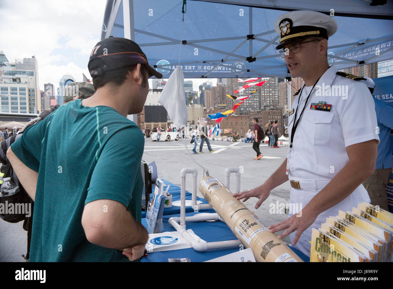 170526-N-MS174-003 NEW YORK (May 26, 2017) Lt. Cmdr. James McLeod, a public affairs officer assigned to U.S. Fleet Forces Command, talks about how sonobouys are used to detect frequencies and signals in the water with a visitor at the U.S. Navy’s “Stewards of the Sea: Defending Freedom, Protecting the Environment” exhibit aboard the amphibious assault ship USS Kearsarge (LHD 3) during Fleet Week New York. The Navy employs every means available to mitigate the potential environmental effects of our activities without jeopardizing the safety of our Sailors or impacting our Navy readiness mission Stock Photo