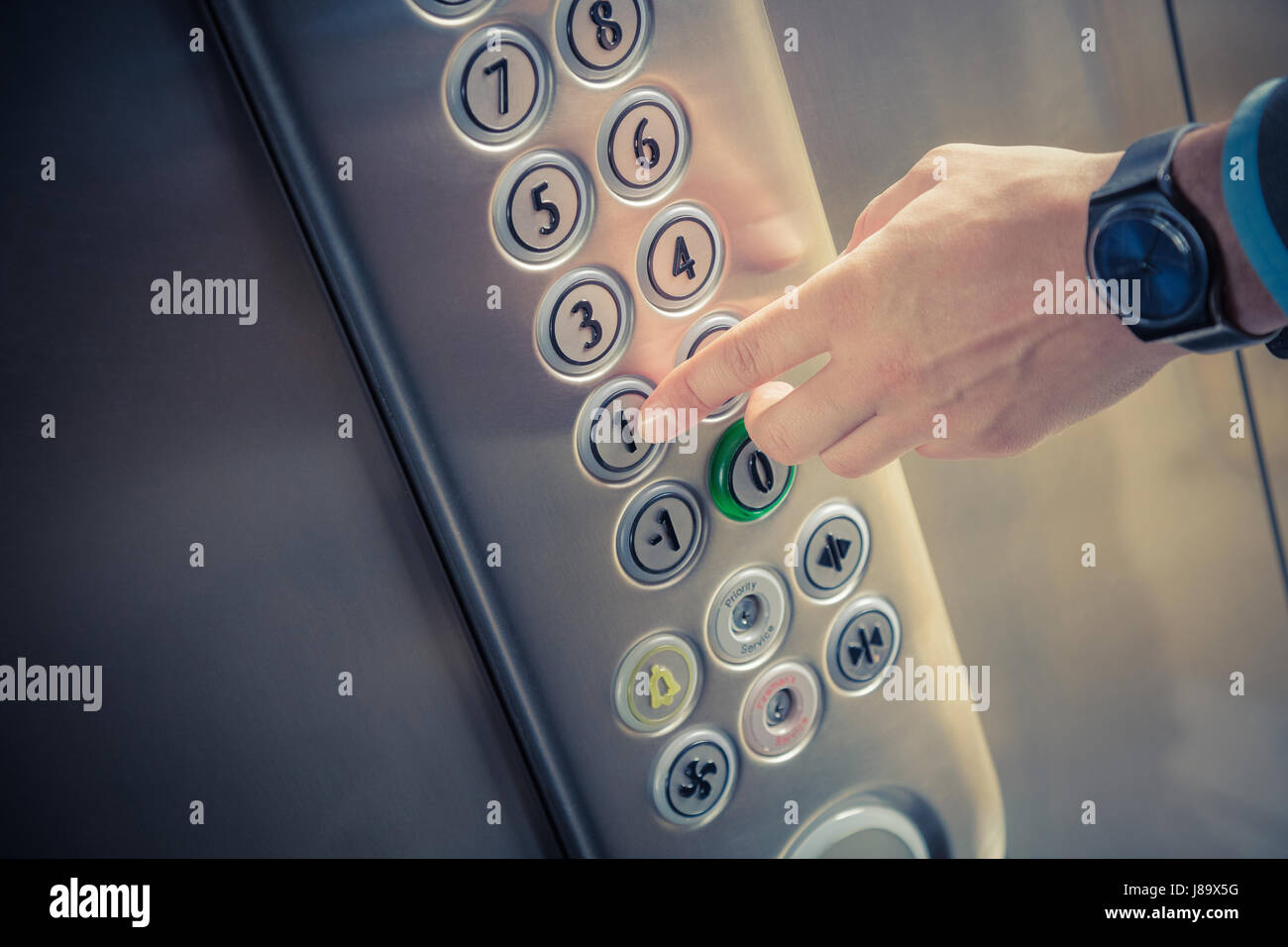 Man pressing the button in the elevator interior Stock Photo