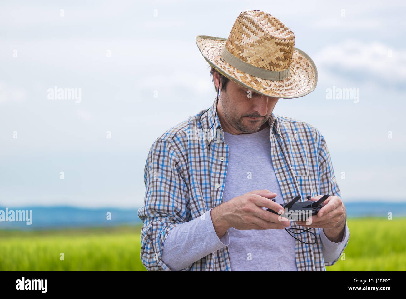 Smart farming concept, farmer using drone remote controller to navigate aircraft in cultivated field and examine crops Stock Photo