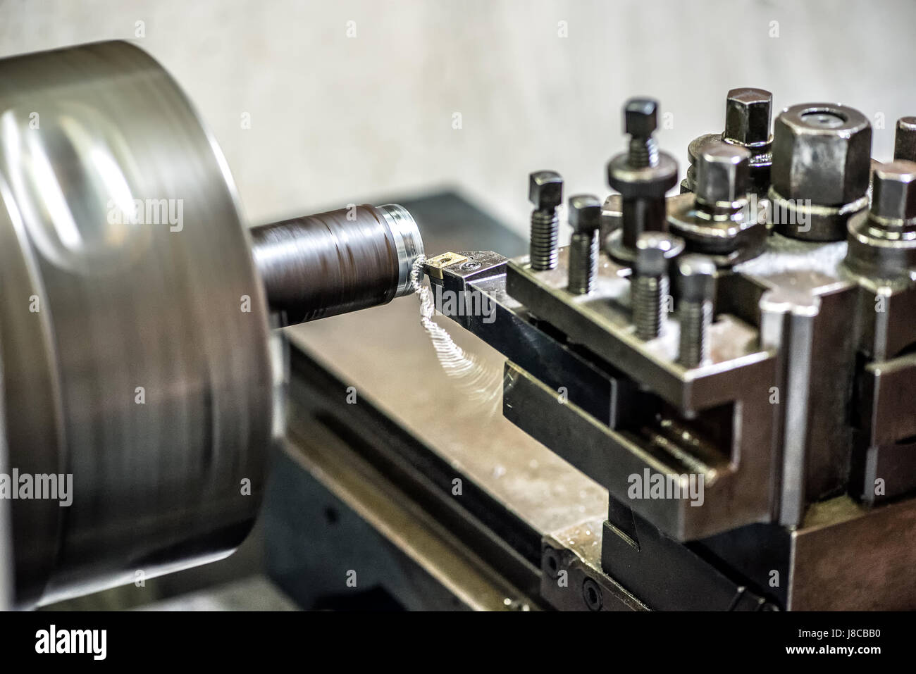 Close-up of lathe machine working with pipe clamped inside the chuck and cutter removing thin layer of metal Stock Photo