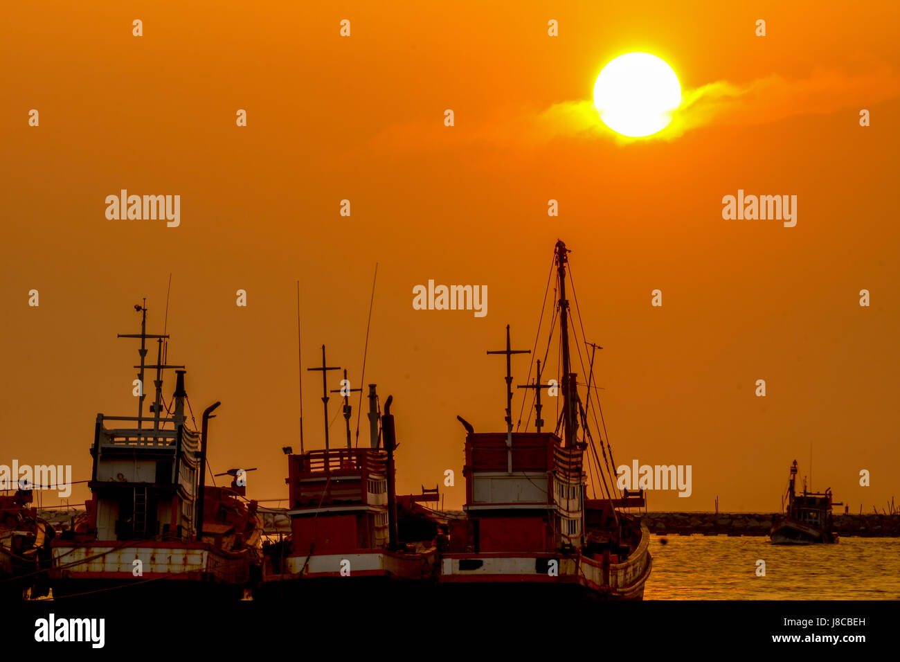 Fishing boats are parking at sea port during sunset Stock Photo - Alamy