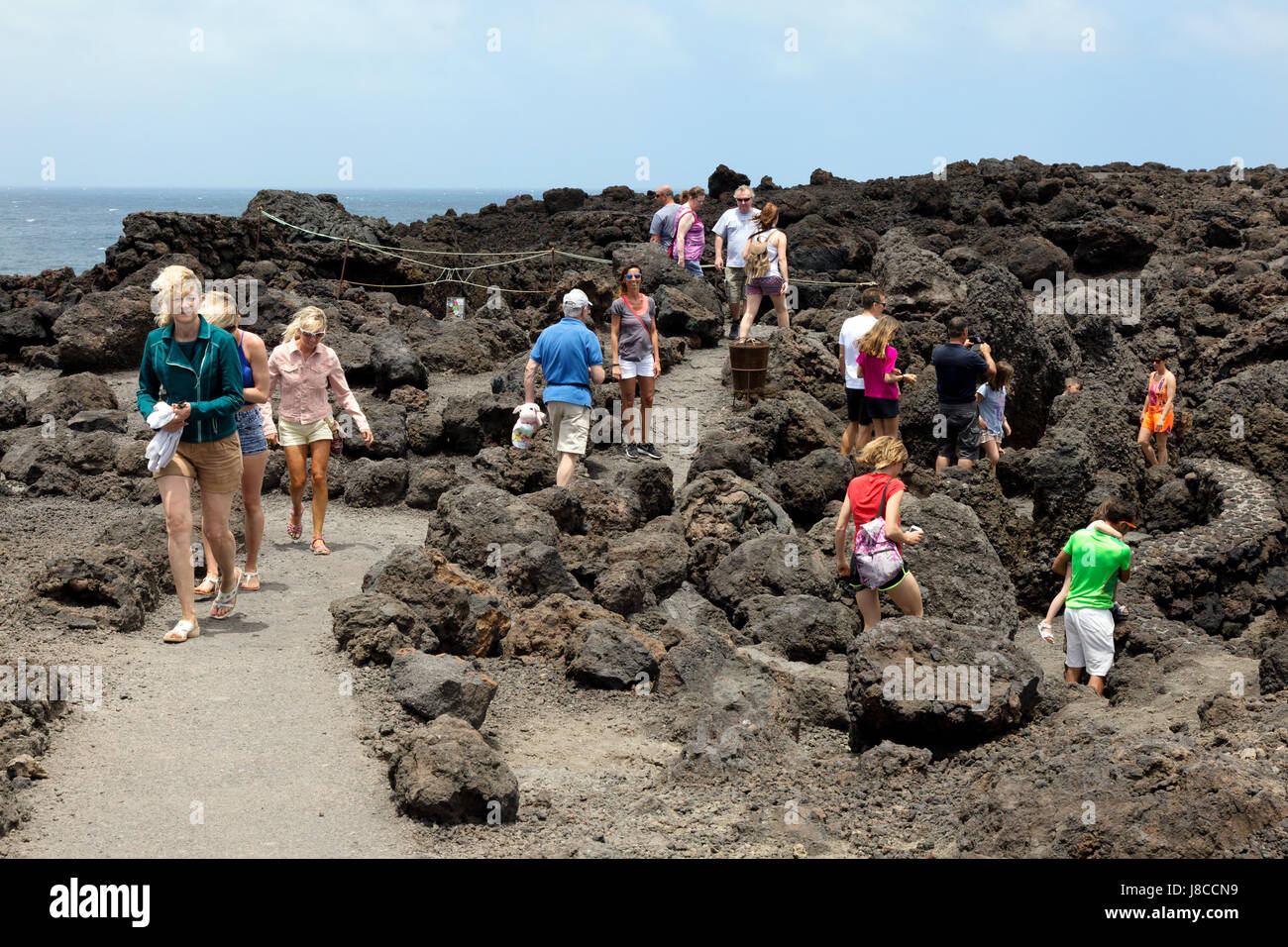 Lanzarote tourism - Tourists walking in the old lava flows at Los Hervideros on the west coast, Lanzarote, Canary Islands, Europe Stock Photo