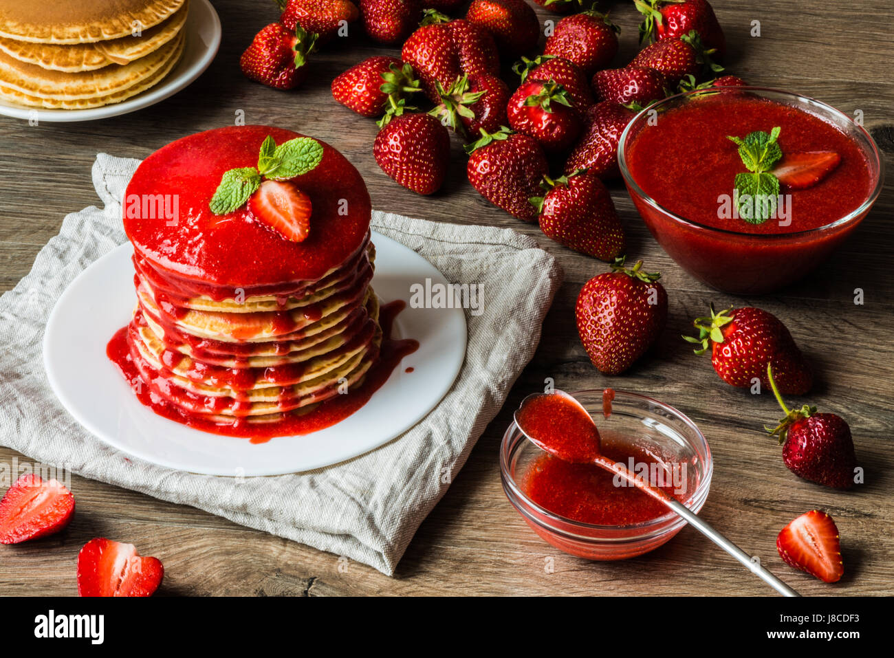 American pancakes and strawberry sauce on a wooden background. Great depth of field. Stock Photo