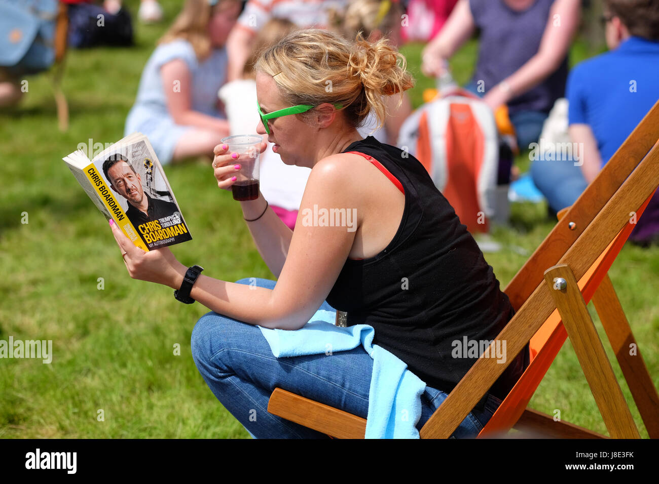 Hay Festival 2017 - Hay on Wye, Wales, UK - May 2017 - Hot sunshine on Day 4 of the Hay Festival - a visitor enjoys reading the new Chris Boardman autobiography Triumphs and Turbulence on the Festival lawns - Credit: Steven May/Alamy Live News Stock Photo