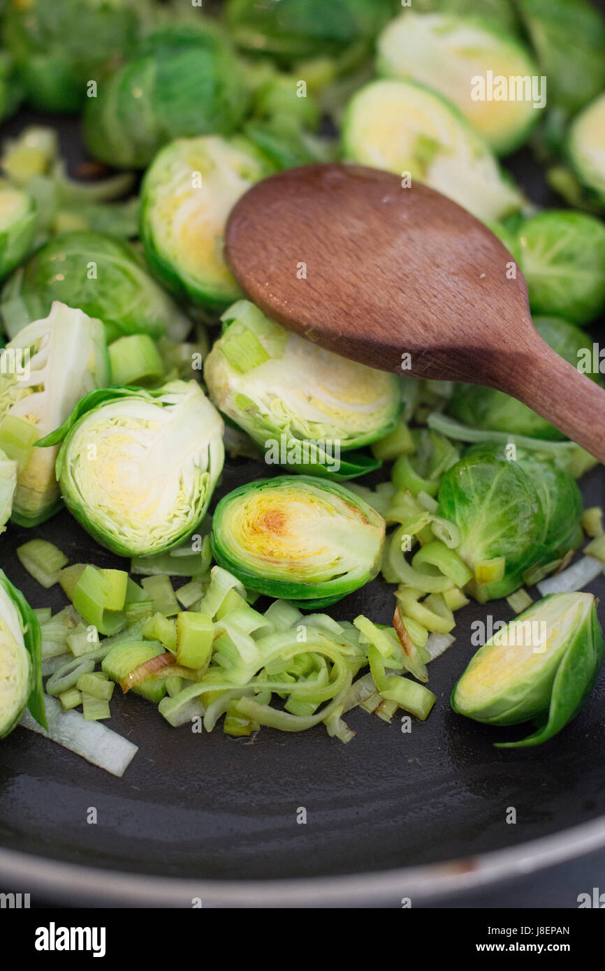 Roasting Brussels sprouts and leek in a pan Stock Photo