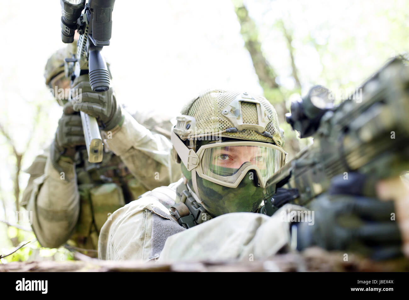 Soldiers with assault rifles ambushed in forest Stock Photo - Alamy