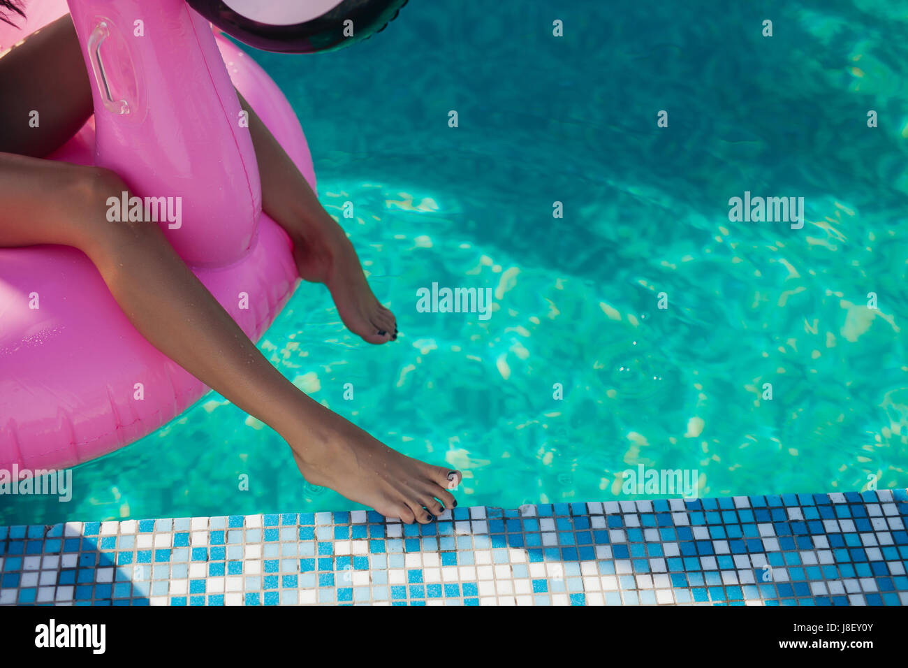 Tan Girl Sits On Inflatable Mattress Flamingos In The Pool Stock Photo tan-girl-sits-on-inflatable-mattress-flamingos-in-the-pool-stock-photo