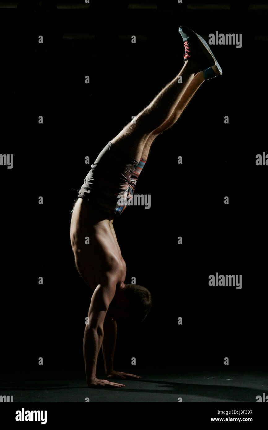 Fitness training. Male athlete walking on his hands or standing upside ...