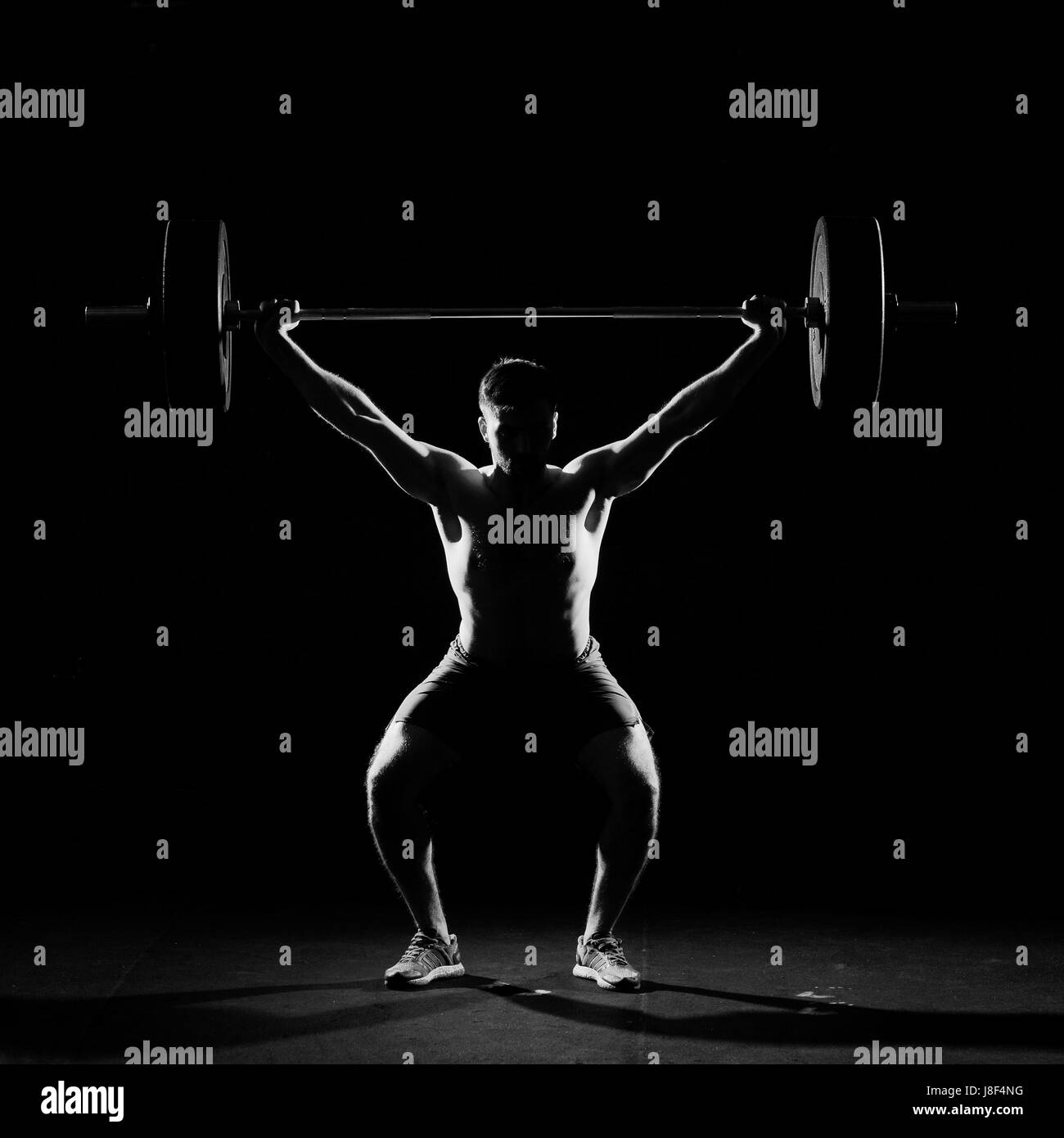 Fitness training. Man doing sit ups exercise with barbell in dark gym