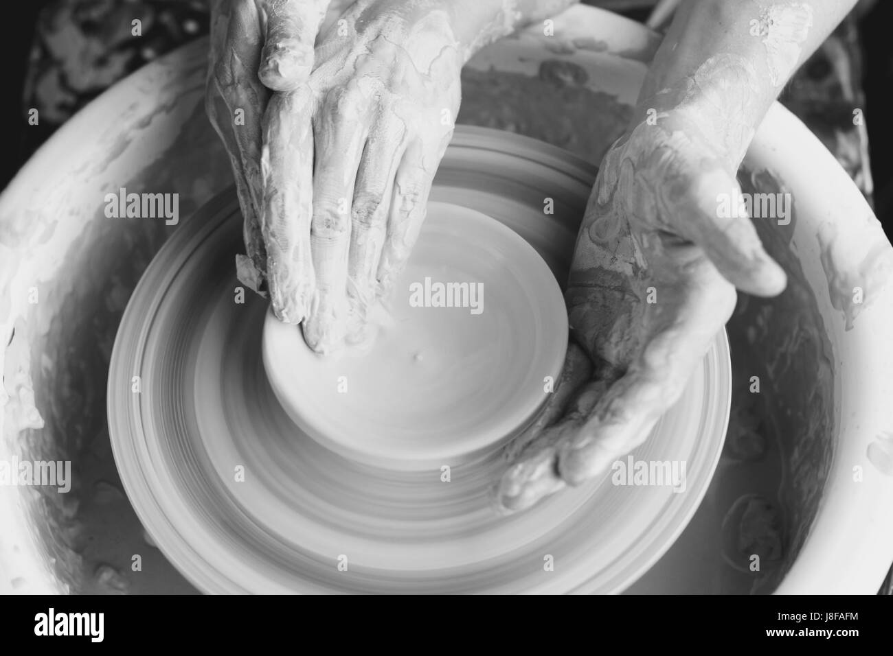 Couple working on pottery wheel. Top view of woman and man hands making ...